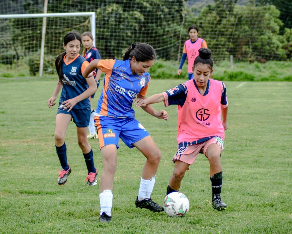Two older girls battling for the ball in a soccer game.